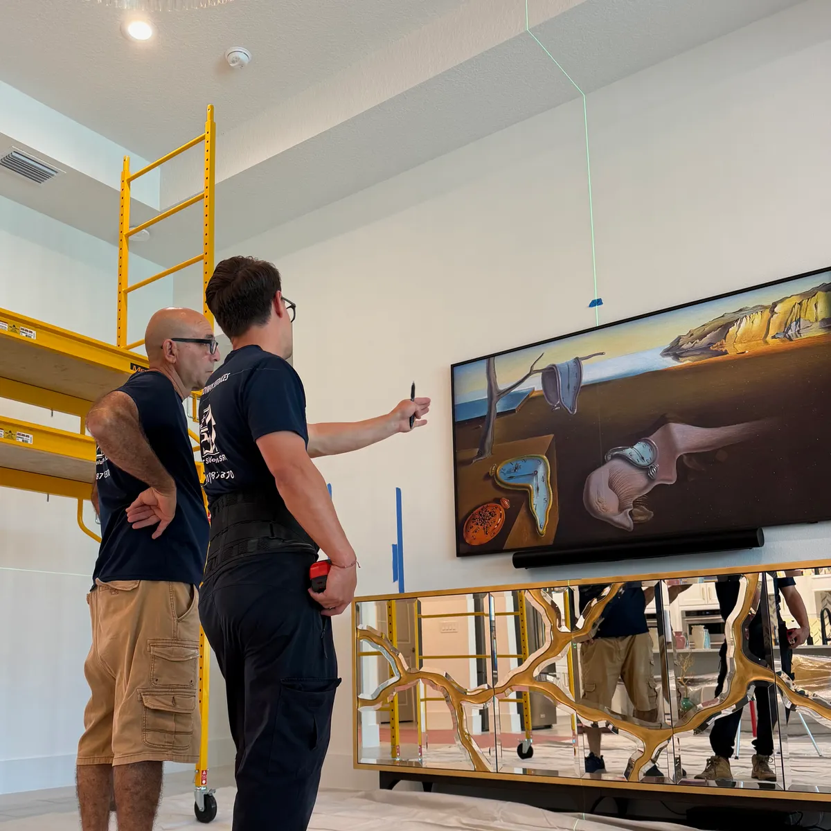 Smart Solutions SRQ team planning a TV and art installation with a laser level in a Sarasota home